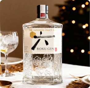 Roku Japanese Gin clear hexagonal bottle with white label and black calligraphy, photographed with a cocktail glass over a holiday background