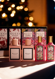 Gucci Bloom and Flora miniature perfume gift set with multiple small pink bottles arranged in a patterned holiday box in front of a festive backdrop