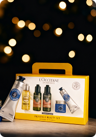 L'Occitane Provence Beauty Set with several skincare products including creams and bottles inside a yellow gift box in front of a festive backdrop.
